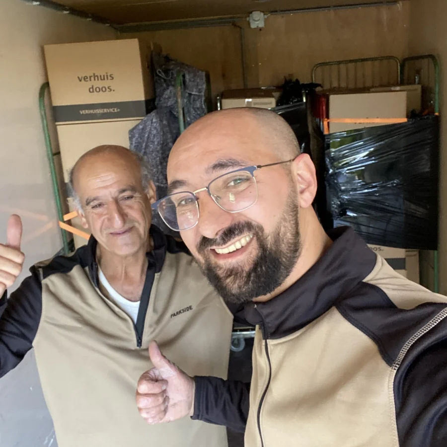 Twee verhuizers van GD Verhuisbedrijf steken hun duim op in een volgeladen verhuiswagen
